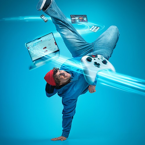 Jugendlicher mit Controller, Laptop, Fernseher und Tablet