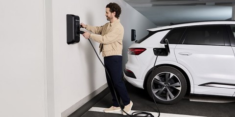 Mann lädt E-Auto an Wallbox.