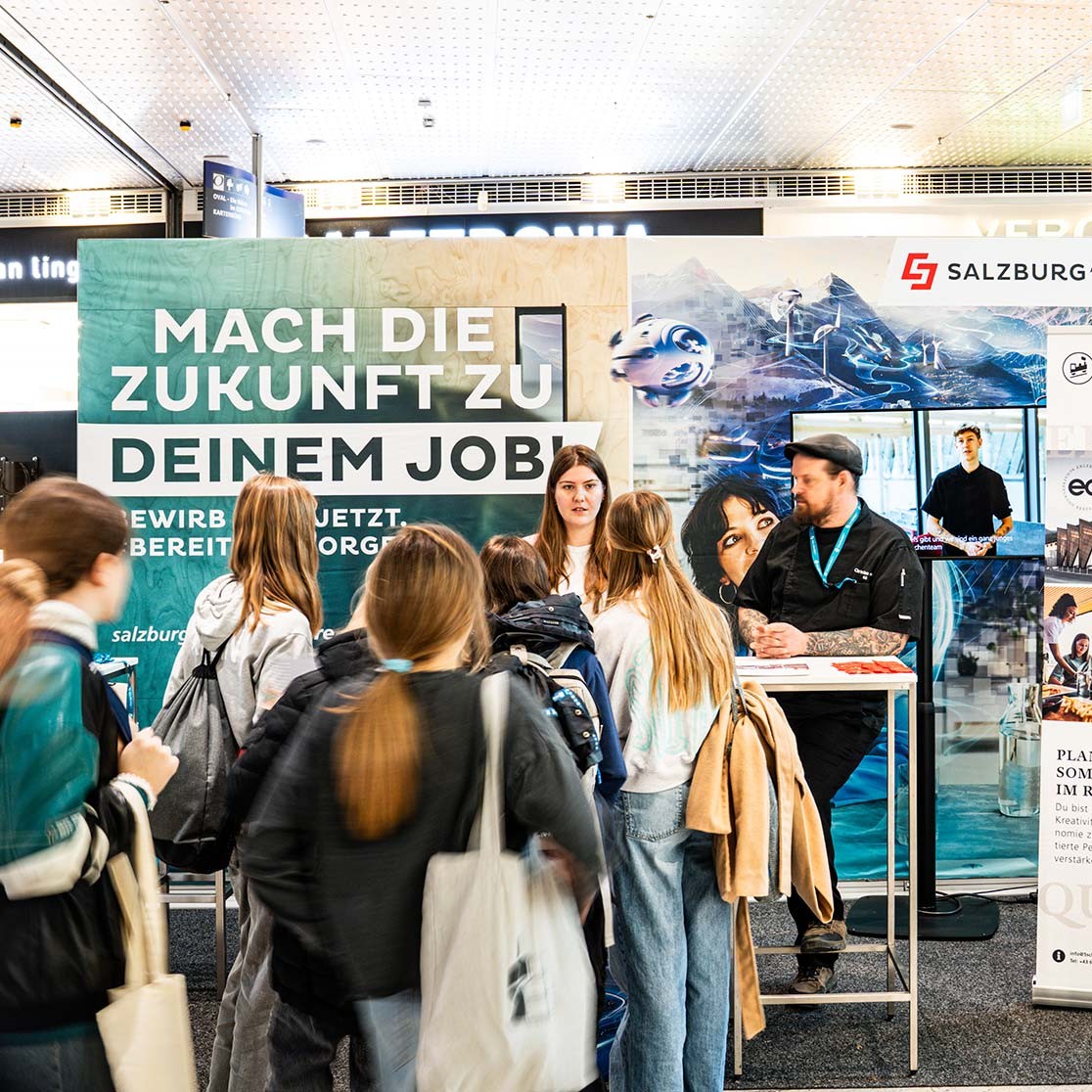 Junge Leute informieren sich auf einer Karrieremesse am Stand der Salzuburg AG