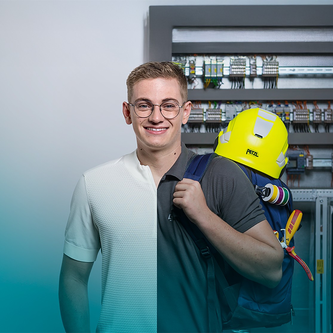 Lehrling steht vor Stromverteilerkasten. Das Outfit ist in der Mitte geteilt: Auf einer Seite Alltagskleidung, auf der anderen Arbeitskleidung.