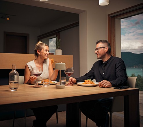 Ein Pärchen sitzt bei einem gemütlichen Dinner mit gedimmten Licht an einem Tisch.